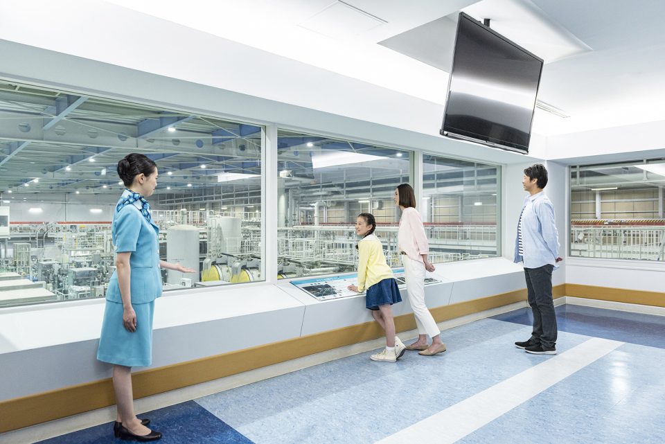 見学通路から製造ラインを見学するお客様と案内係